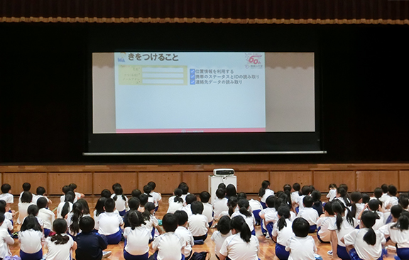 体育館でインターネットの注意点をきく児童