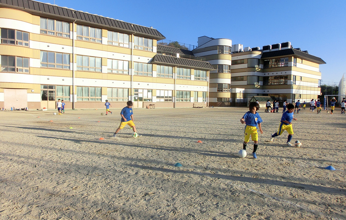 運動場でサッカーをする子供たち
